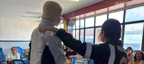 Pessoa em pé segurando um boneco e simulando atendimento