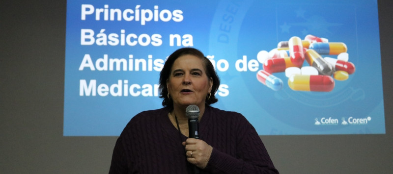 Pessoa em pé apresentando conteúdos para alunos em uma sala