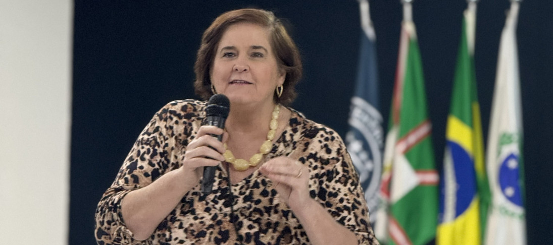 Pessoa em pé falando para outras pessoas que estão sentadas em uma sala
